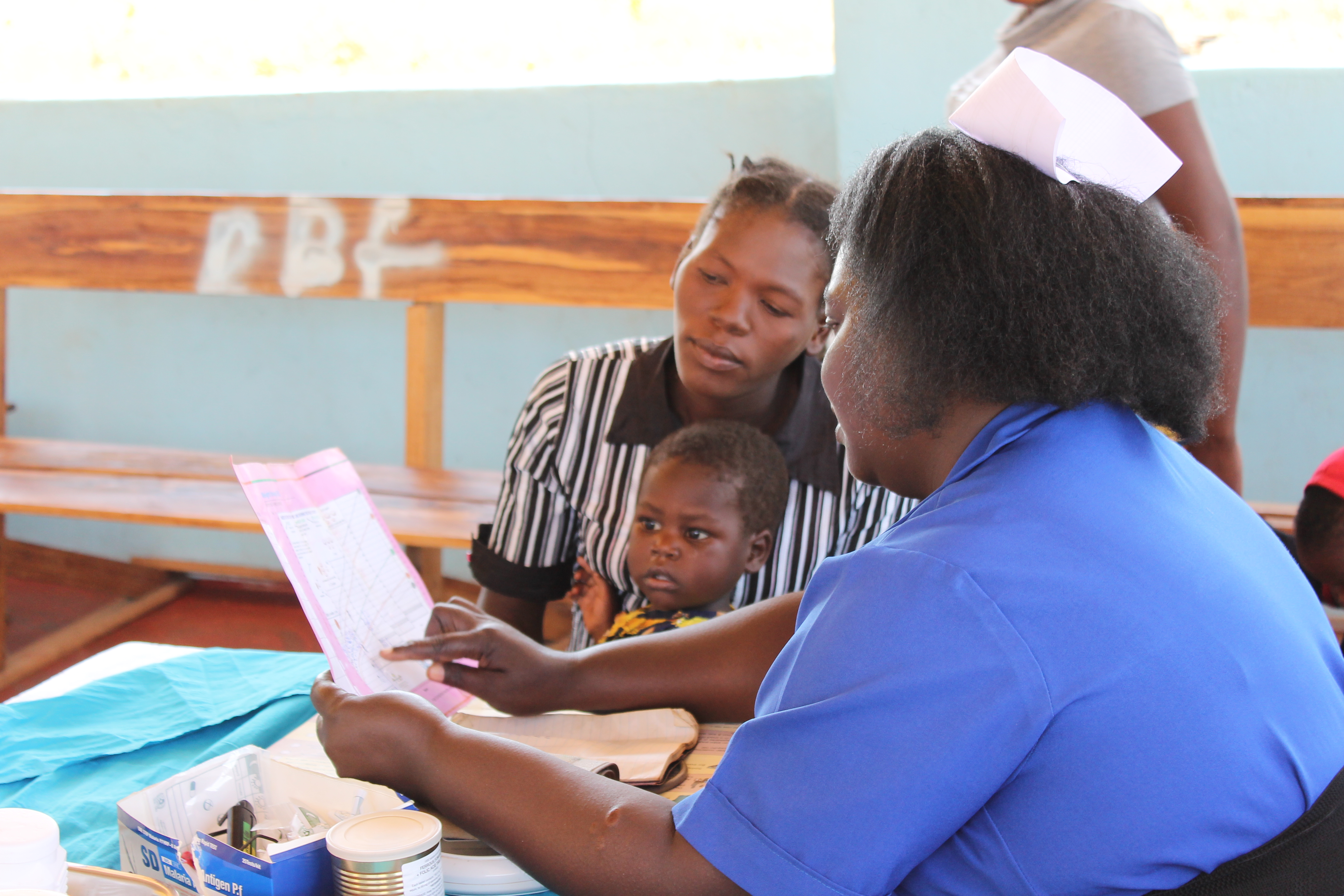 Nurse performs a checkup with a woman and child at Lundazi Urban Clinic