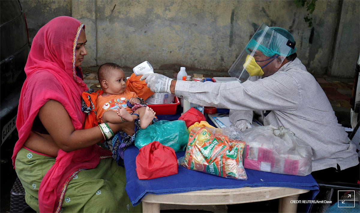 A doctor wearing a protective face shield uses an infrared thermometer to measure the temperature of a child at his mobile health clinic, after his clinic and its adjoining areas were declared a micro-containment zone, after authorities eased lockdown restrictions that were imposed to slow the spread of the coronavirus disease (COVID-19), in Ahmedabad, India, June 15, 2020. REUTERS/Amit Dave
